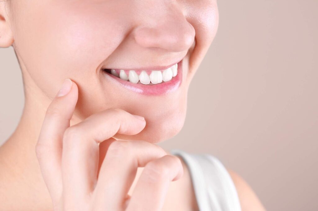 Η γυναίκα δείχνει το αποτέλεσμα της ασφαλούς εξαγωγής δοντιού με φυσικό και λαμπερό χαμόγελο.