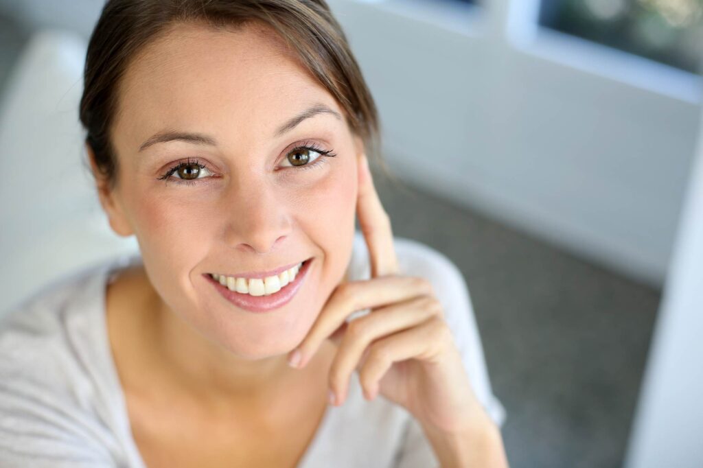 Η γυναίκα δείχνει υγιή ούλα και δόντια, αποτέλεσμα της περιοδοντικής θεραπείας και της φροντίδας.