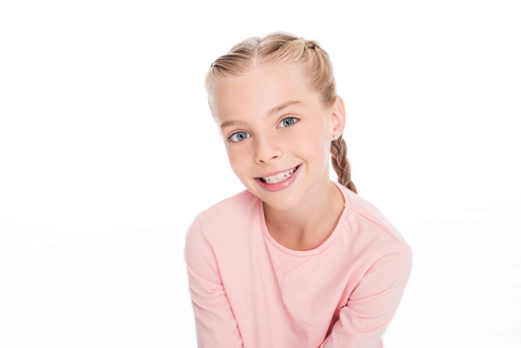 Το κορίτσι επιδεικνύει το αποτέλεσμα της πρόληψης του συνωστισμού των δοντιών με το μηχάνημα διατήρησης χώρου.