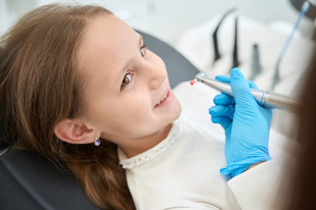 Το κορίτσι λαμβάνει παιδικά σφραγίσματα για την πρόληψη της τερηδόνας σε ένα ασφαλές περιβάλλον.