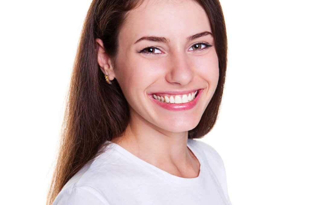 Η γυναίκα δείχνει το αισθητικό αποτέλεσμα της αποκατάστασης δοντιών με σύνθετη ρητίνη και βιοσυμβατότητα.